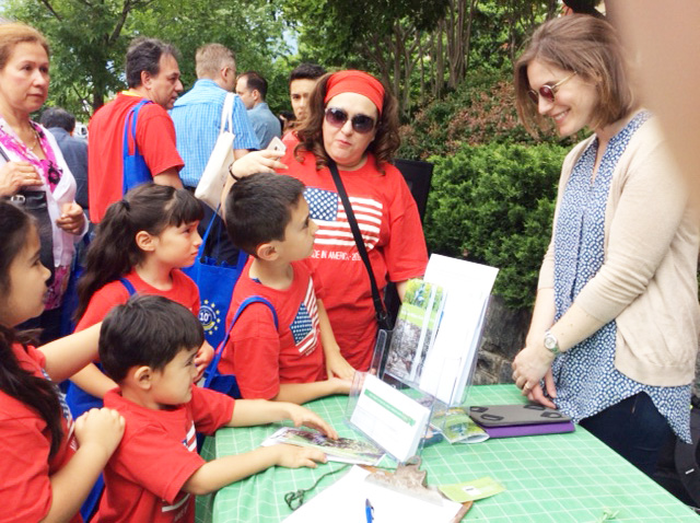 A young woman explains the work of RMA to a family gathered at an outdoor table