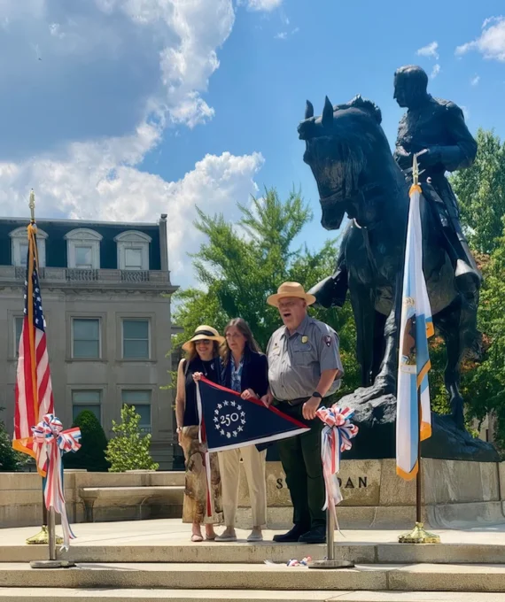 Representatives of a neighborhood group, the US Dept. of Interior, and National Park Service stand in front of equestrian statue of Sherman.